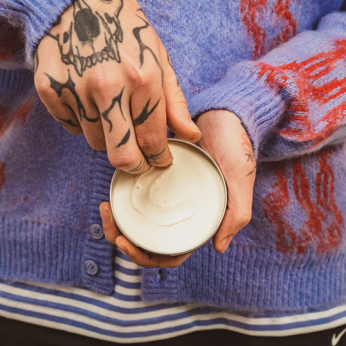 Person holding a Reuzel container with a Severed Head Pomade