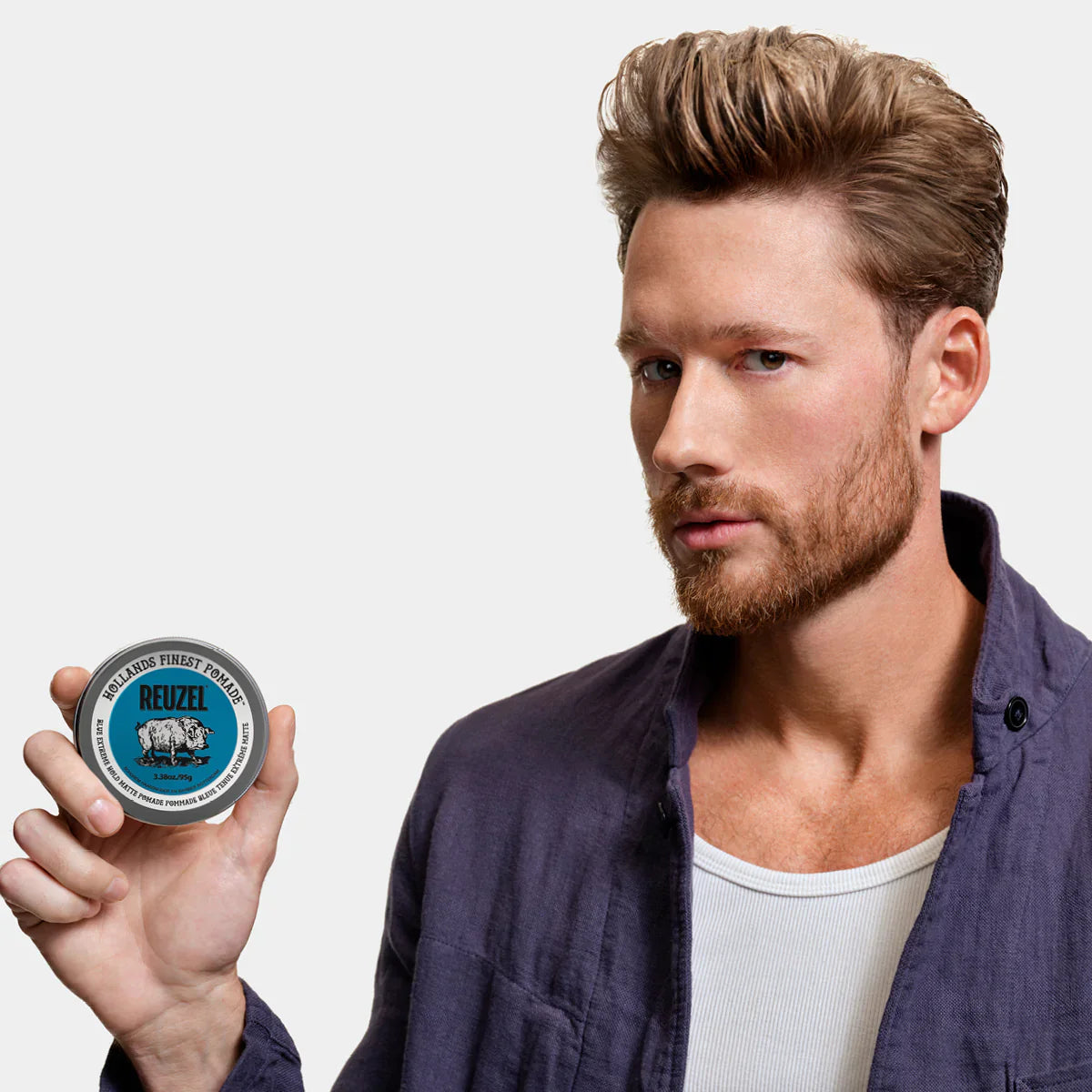 Reuzel Blue Extreme Hold Matte Pomade jar with black lid, showcasing the product label and textured blue packaging.